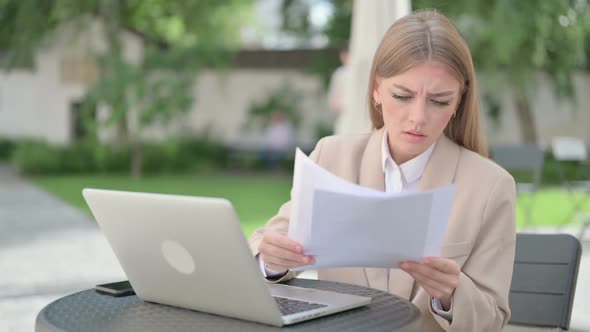 Young Businesswoman with Laptop Celebrating While Reading Documents alt