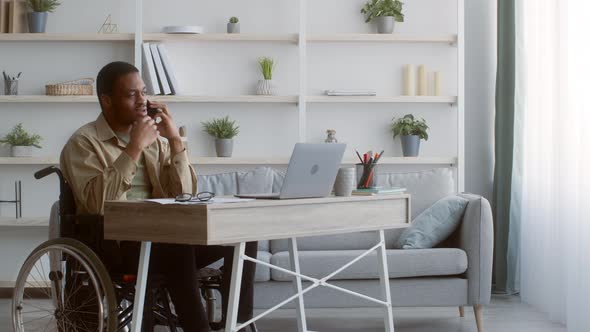 Disabled Black Man Talking On Phone In Wheelchair Working Indoors alt