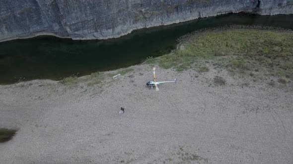 A Helicopter with Spinning Blades in Nature Near a River Begins To Take Off