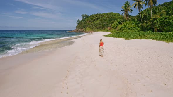 Camera Follows Young Woman As She Walks on the Paradise Anse Bazarca Beach alt