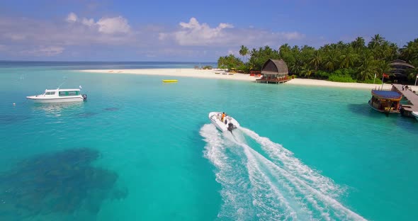 Aerial drone view of a man water skiing near a tropical island alt