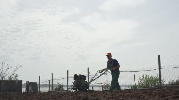 Man Plowing the Land in the Garden on Sky Background