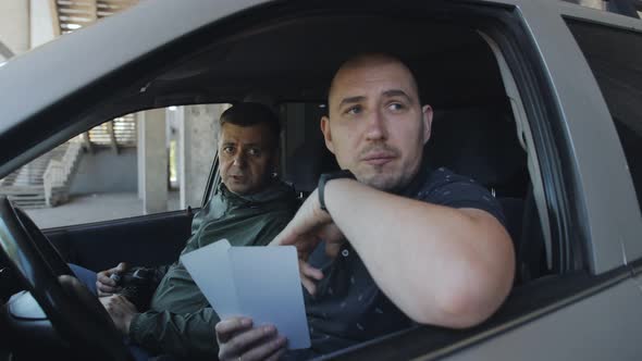 Two Plainclothes Police Officers or a Spy Take Covert Photos of Illegal Actions From the Car Window alt