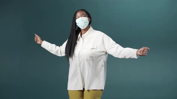 A Young Black Woman is Dancing in a Medical Protective Mask Gaily