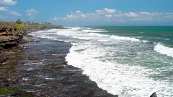 Aerial View 4K Waves Break On Dark Rocks Near Beach. Sea Waves On The Stones