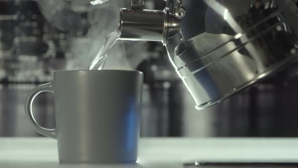 Pouring hot water from the metal teapot alt