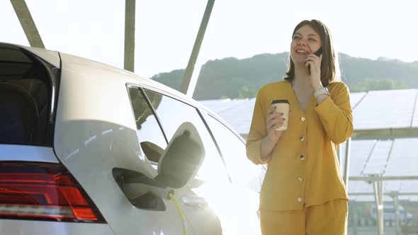 Woman Taking Phone Call Standing Near Her Electric Car