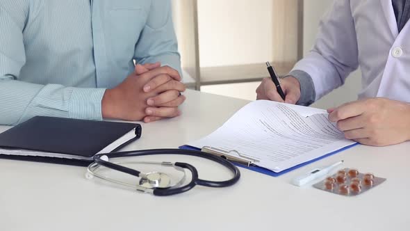 Doctor is signing a medical certificate about the patient's symptoms at the office.