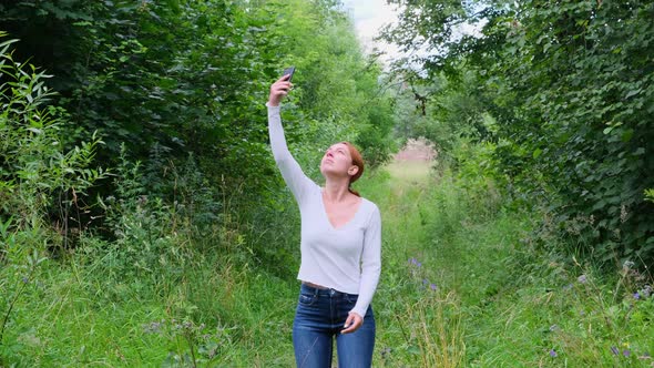 Woman Trying To Pick Up the Signal on Her Mobile Phone in the Forest alt