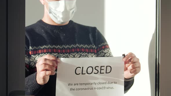 Male Hanging a Sign Closed on the Door alt