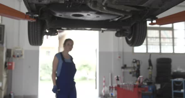 Professional female mechanic working under a car in the auto repair shop
