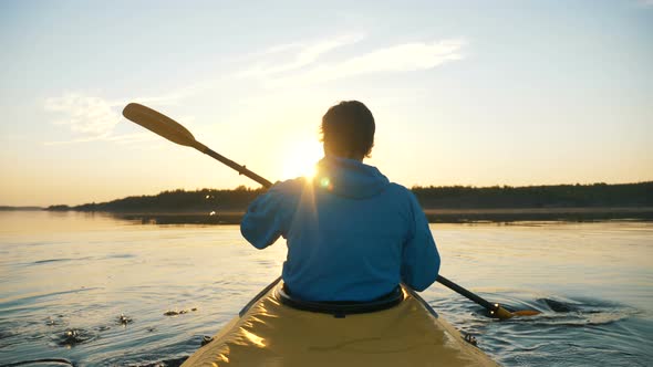 Outdoor Activities Unity with Nature, Man Kayaking on Calm Lake Against Sunset Rays alt
