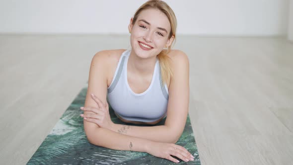Delighted Sportswoman Lying on Mat in Studio alt