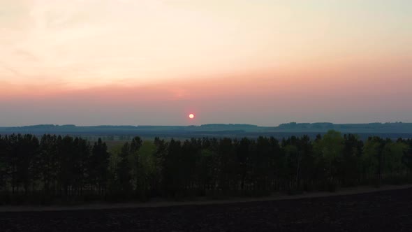 Aerial View of the Red Sunset Over the Forest alt