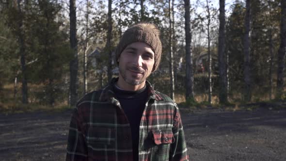 Cheerful traveler smiling at camera in forest alt