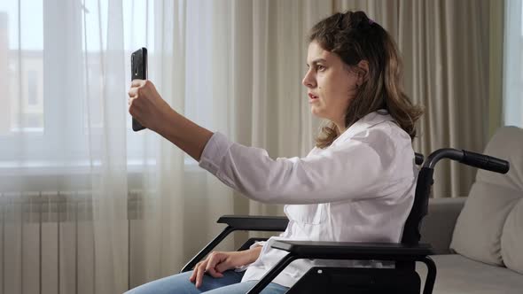 Disabled Woman in Wheelchair Talks on Videocall at Home alt