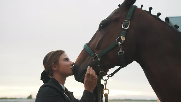 Female Horse Owner Holding Bridle Of Her Horse And Kissing Her Horse With Love alt