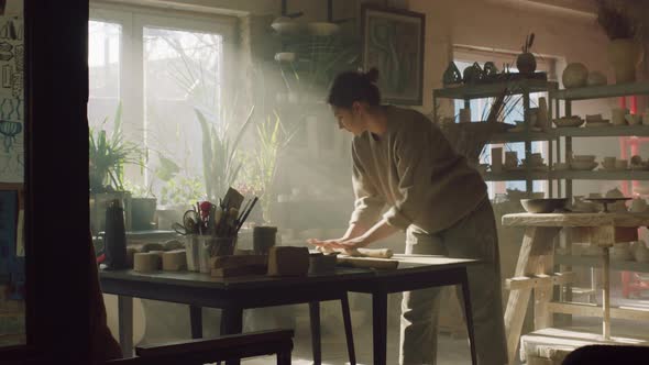 Young Woman Is Rolling Out Piece of Raw Clay alt