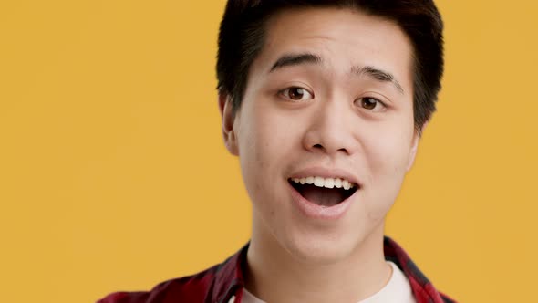 Cheerful Chinese Young Man Gesturing OK Sign Over Yellow Background alt