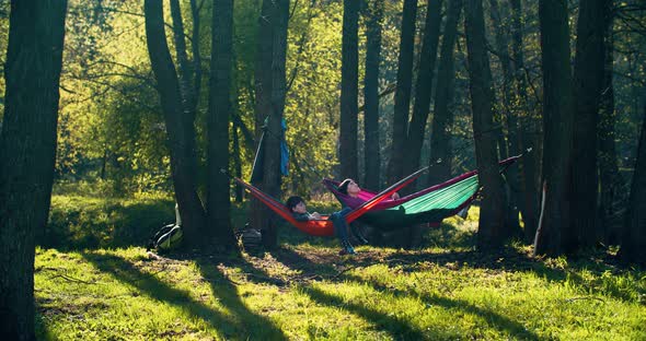 The family is resting in nature. In hammocks stretched out on trees. 