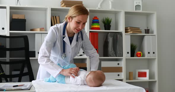 Pediatrician Raising Child Arm Lying on Table