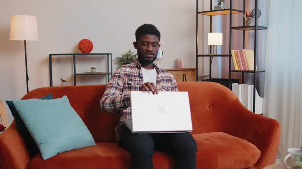 African American Man Sitting on Sofa Opening Laptop Pc Starting Work Online in Living Room at Home alt