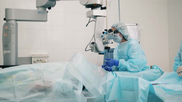 Ophtolmologist in Eye Hospital. Female Doctor Is Operating with an Eyesight Medical Machine alt