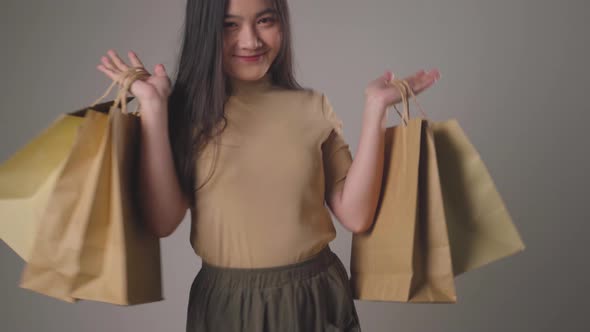 Confident asian woman happy holding shopping bag dancing smilling and looking at camera