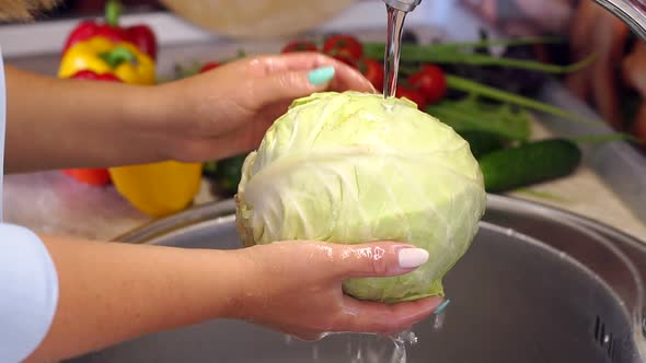 Closeup of Young Woman Washing Fresh Cabbage in Sink Under Running Water alt