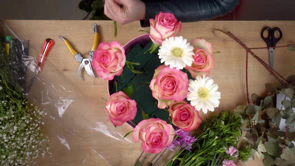 Top view of the hands of a young female florist creating a composition alt