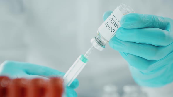 Doctor Picks Up Coronavirus Vaccine with a Syringe alt