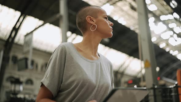 Worried bald woman looking around and reading her e-book alt