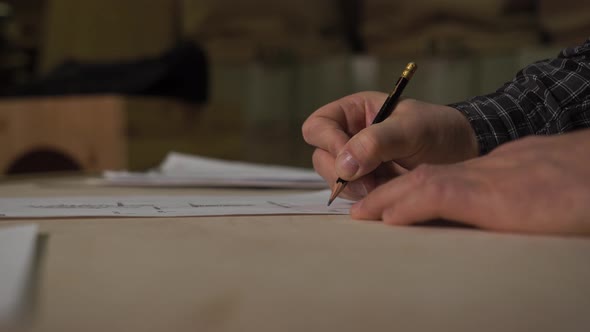 Man Puts Glasses on His Face in the Garage of Workshop at Home Looking at Work alt