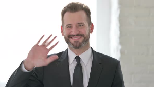 Middle Aged Businessman Waving Hand to Say Hello alt