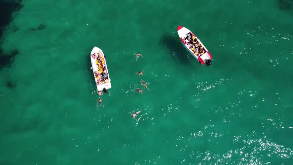 Aerial Photos of People Swimming and Diving Next to Boats in the Emeraldturquoise Crystal Clear Sea alt