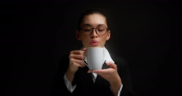 Woman in Glasses and Office Clothes Drinks Hot Tea in a White Mug