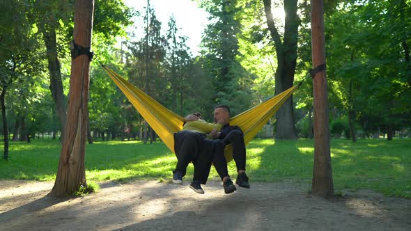 Young couple embracing while lying in hammock alt