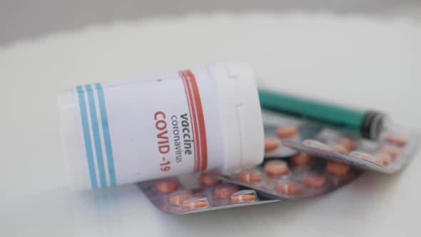 Rotating view of covid-19 vaccine bottle over tablets packets