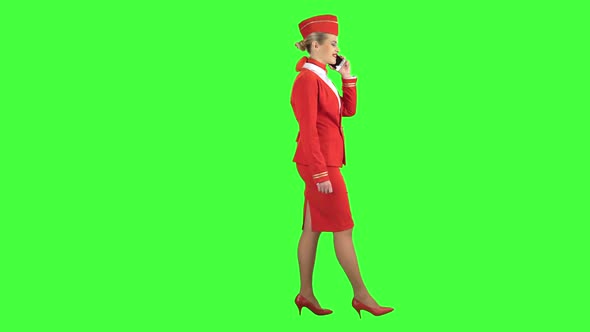 Stewardess Speaks on the Phone and Paces Into the Distance. Green Screen. Side View alt