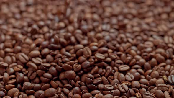 Roasted Coffee Beans Drop in Slow Motion on Full Frame Background of Coffe Beans