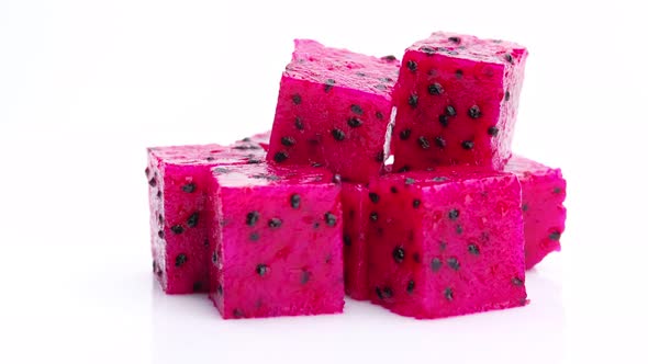 Red Dragon fruit (Pitaya) cut pieces, cubes isolated on white background. Rotating shot
