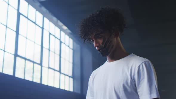 African american man with hand mark on their mouth standing in empty parking garage alt
