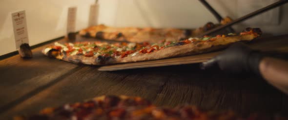Delicious al taglio pizzas with different toppings being placed on a wooden surface in a pizza cafe. alt