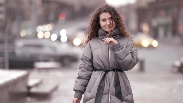 Positive Woman Dressed Down Jacket Is Walking in City at Winter Day Snowless Season in Town alt