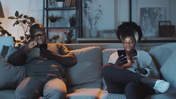 Afro-American Family Couple Using Smartphones in the Evening at Home alt