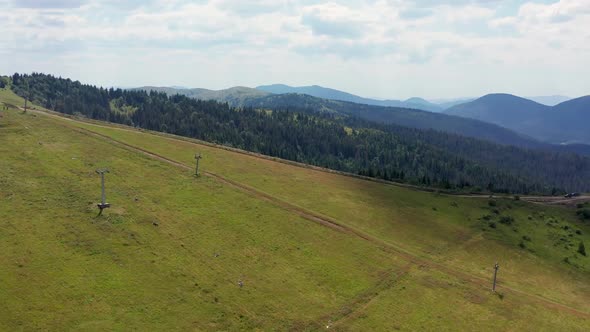 People walk on a chairlift above slope of mountain