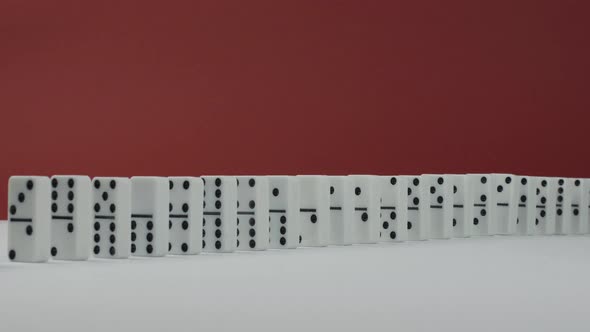 Domino Effect - a Series of Dominoes Falling Down the Chain on Red Background alt