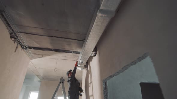 Silhouette of a Construction Worker Laying Ventilation Ducts. Worker Working on a Ladder in a New alt