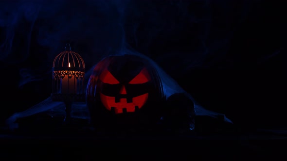 Scary laughing pumpkin and an old skull over the frightening gothic background. alt
