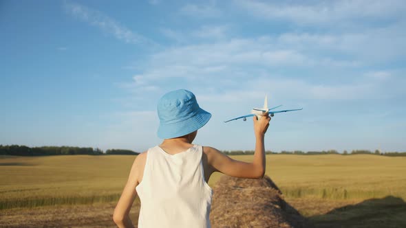 Funny Boy Runs Through the Haystacks and Playing with Airplane Near Wheat Field Boy Dreams of Being alt